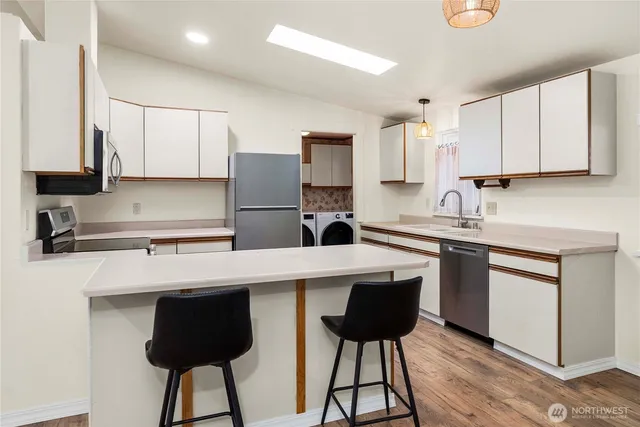 a kitchen with a sink a stove a refrigerator and white cabinets with wooden floor