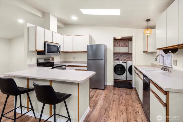a kitchen with stainless steel appliances a stove refrigerator sink and wooden floor