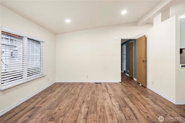 a view of an empty room with wooden floor and a window