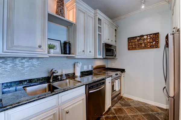a kitchen with stainless steel appliances granite countertop a coffee maker on granite counter tops and white cabinets next to a window
