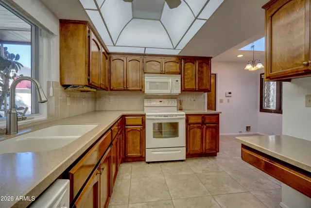 a kitchen with stainless steel appliances granite countertop a sink a stove and a wooden cabinets