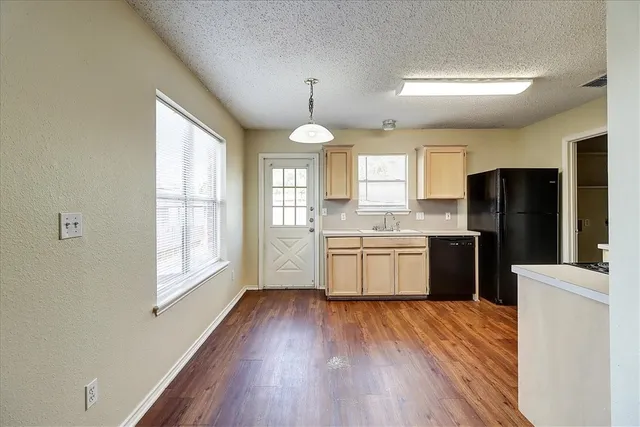 a kitchen with stainless steel appliances a refrigerator a sink cabinets wooden floor and a window