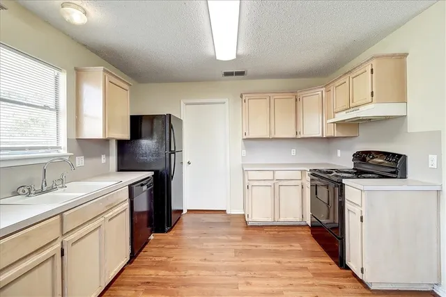 a kitchen with stainless steel appliances granite countertop a stove a sink dishwasher and a refrigerator with wooden floor