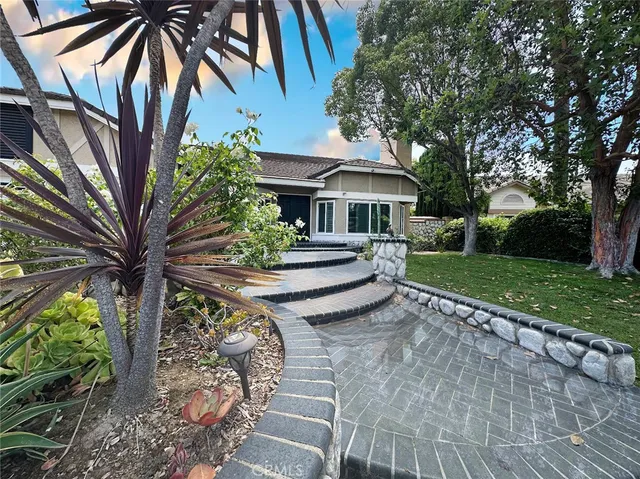 a view of house with a yard and potted plants