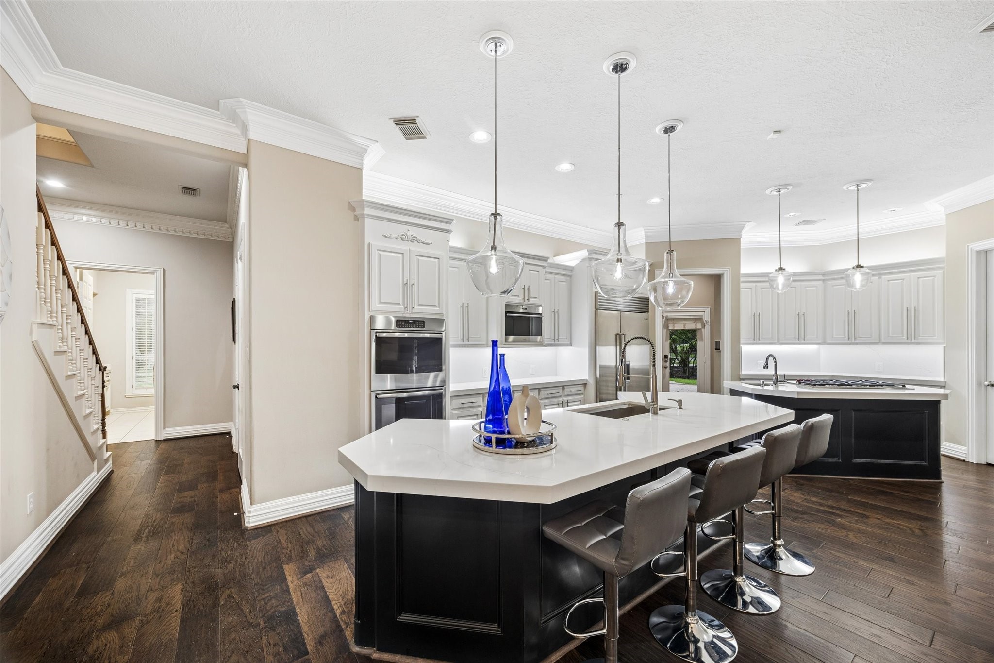 35 North Regent Oak Spring, TX 77381 - Photo 14 of 43 Designed for both the passionate cook and effortless entertaining, this exceptional chef’s kitchen features elegant quartz countertops, custom cabinetry, rich hardwood floors, and dual islands offering generous prep, serving, and gathering space. A primary sink and secondary prep sink enhance functionality, while premium appliances—including a Sub-Zero refrigerator, Bosch dishwasher, GE double ovens, and a Wolf microwave—provide the performance expected in a home of this caliber.