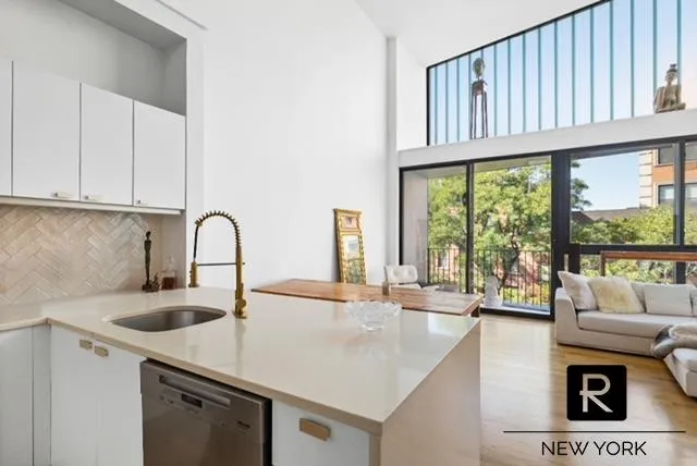 a kitchen with a sink a counter top space and a view of living room