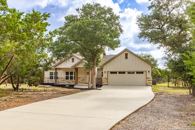 a front view of a house with a yard covered with trees