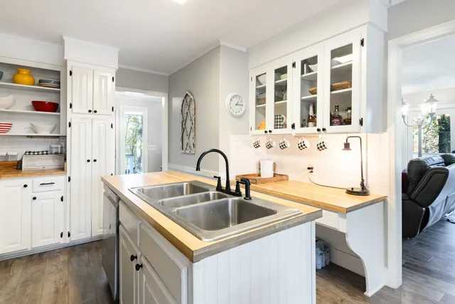 a kitchen that has a sink a stove and a microwave oven with white cabinets