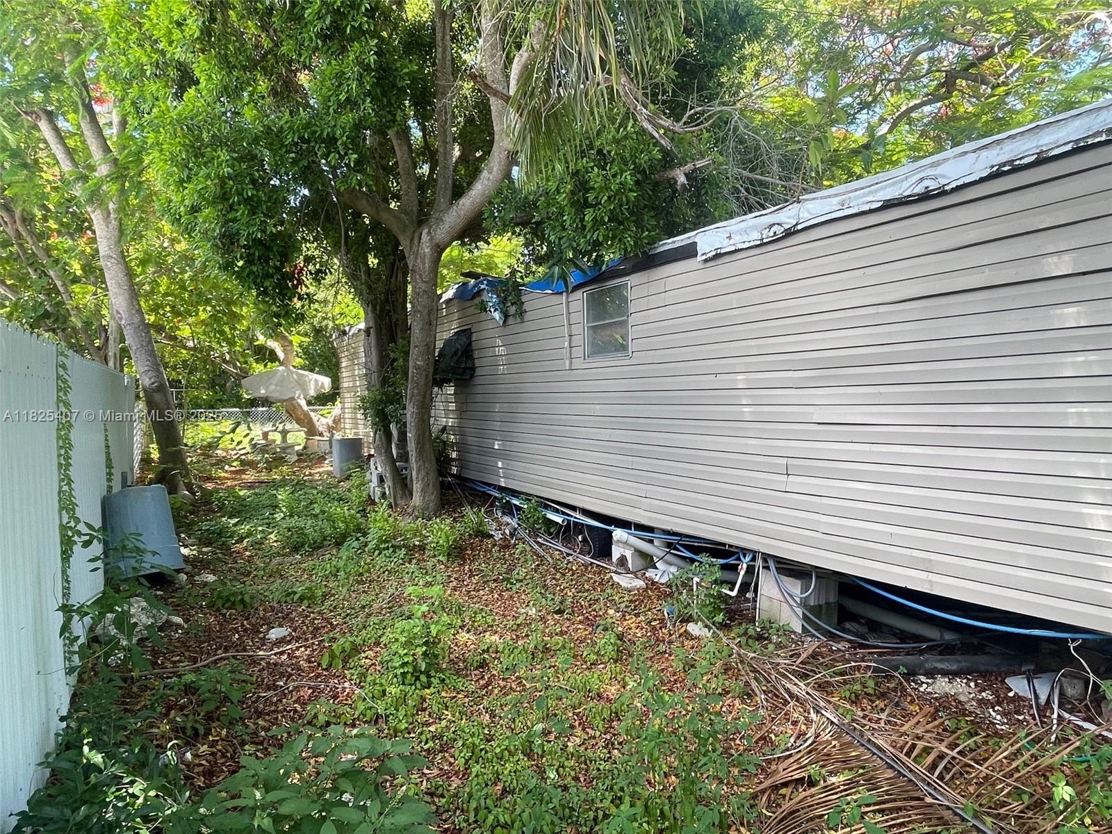Lake Surprise Estates Key Largo, FL 33037 - Photo 3 of 6 a small yard with a table and chair and a large tree