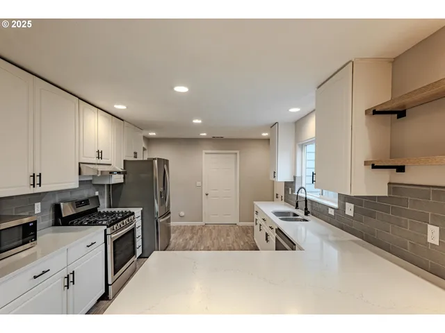 a kitchen with stainless steel appliances kitchen island granite countertop a sink refrigerator and cabinets