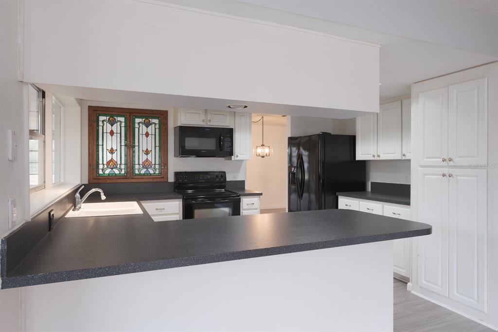 4814 Prince George Circle New Port Richey, FL 34655 - Photo 23 of 75 a kitchen with kitchen island a sink dishwasher a stove and refrigerator with wooden floor