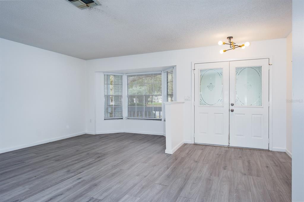 4814 Prince George Circle New Port Richey, FL 34655 - Photo 9 of 75 wooden floor in an empty room with a window