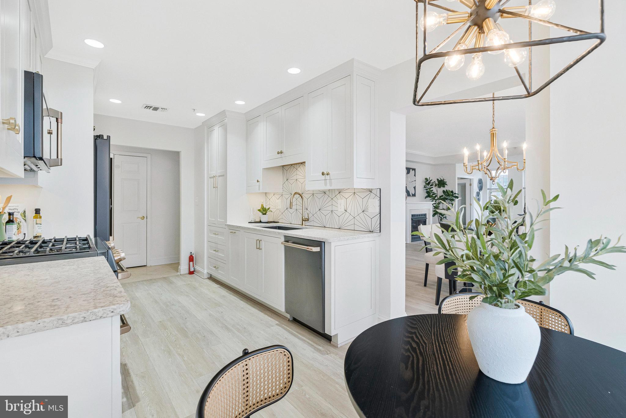 11776 Stratford House Place, Unit 807 Reston, VA 20190 - Photo 5 of 25 a kitchen with stainless steel appliances granite countertop a refrigerator a stove a sink a dining table and chairs with wooden floor