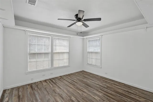 a view of empty room with wooden floor and fan