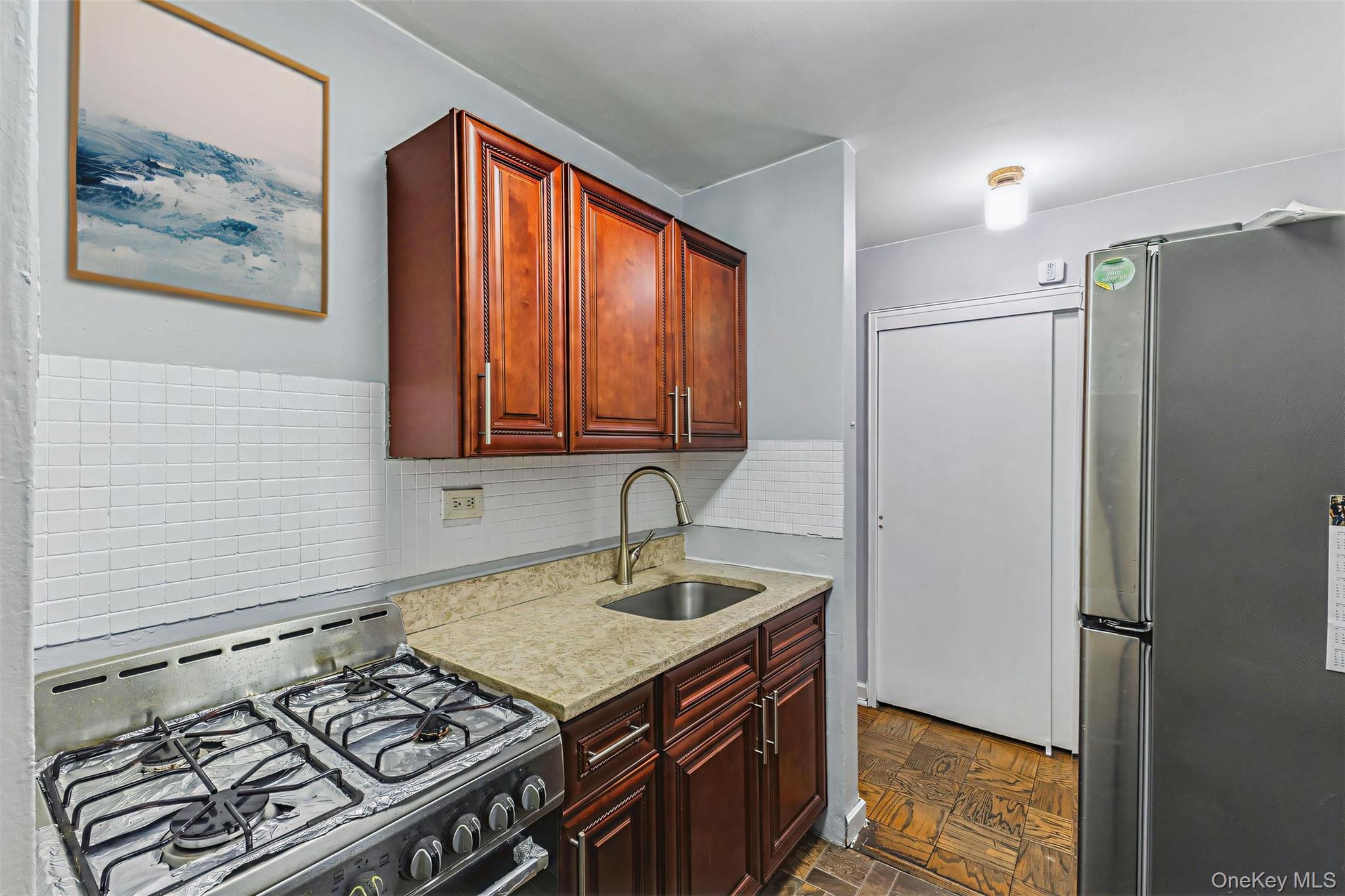 99-10 60th Avenue, Unit 1A Queens, NY 11368 - Photo 5 of 10 Kitchen featuring appliances with stainless steel finishes, light stone counters, decorative backsplash, and dark brown cabinets