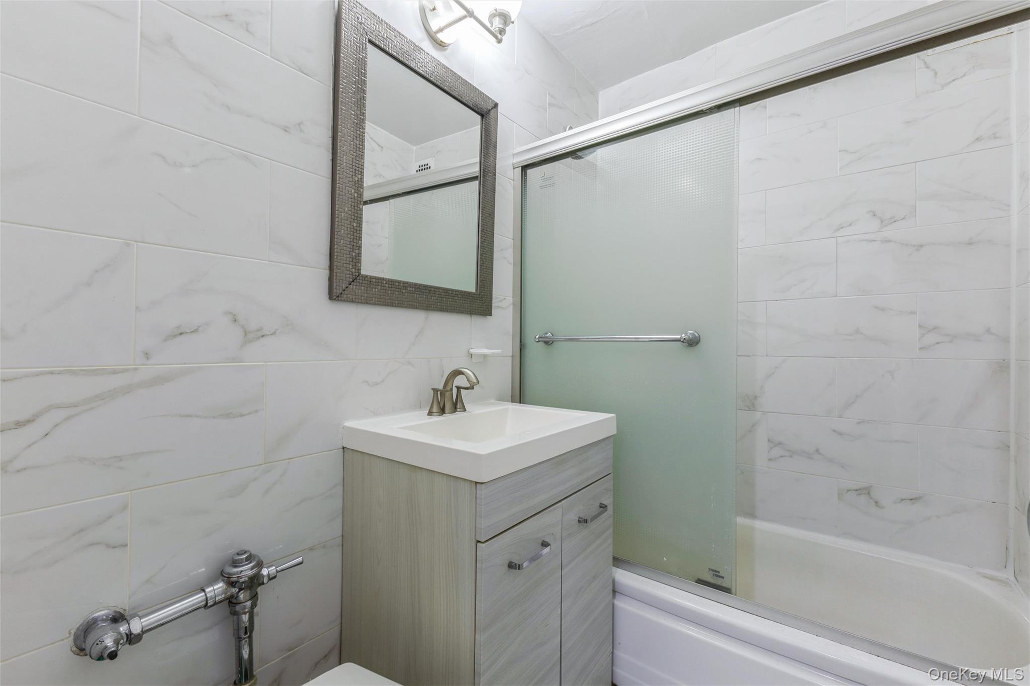 99-10 60th Avenue, Unit 1A Queens, NY 11368 - Photo 6 of 10 Full bathroom with vanity, tile walls, and enclosed tub / shower combo