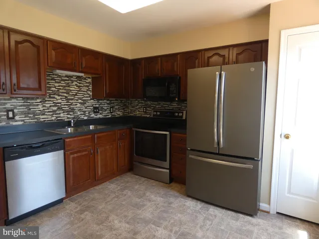 a kitchen with stainless steel appliances granite countertop a refrigerator and a sink