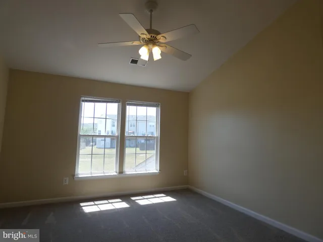 an empty room with windows and chandelier fan