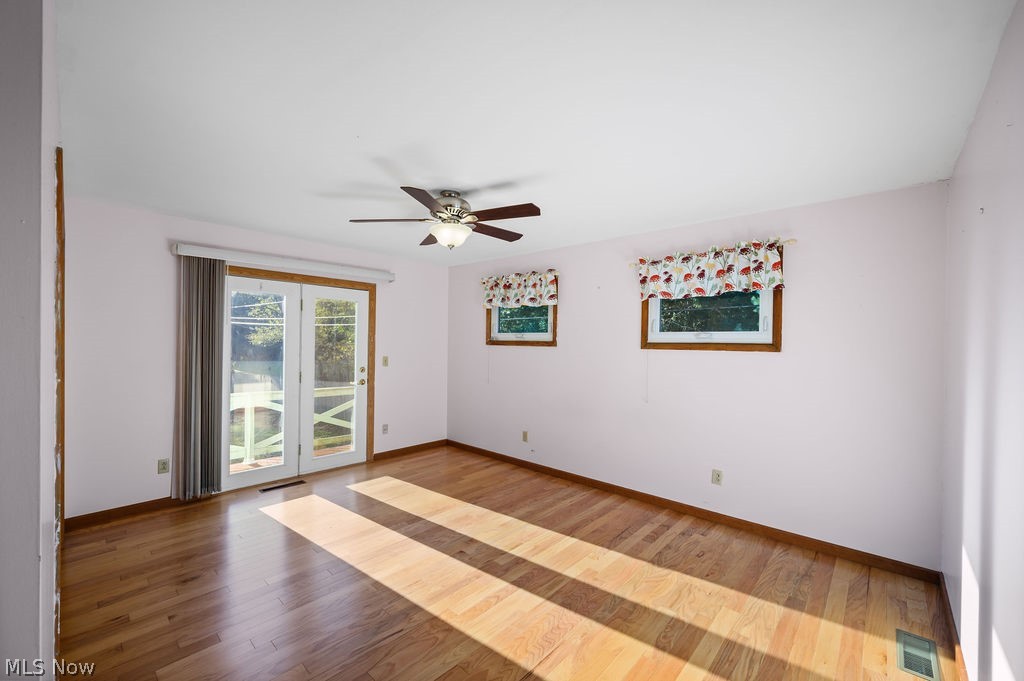 11363 Dupont Road Washington, WV 26181 - Photo 13 of 42 Hardwood flooring throughout, ceiling fan with integrated lighting, two framed windows, and a set of French doors