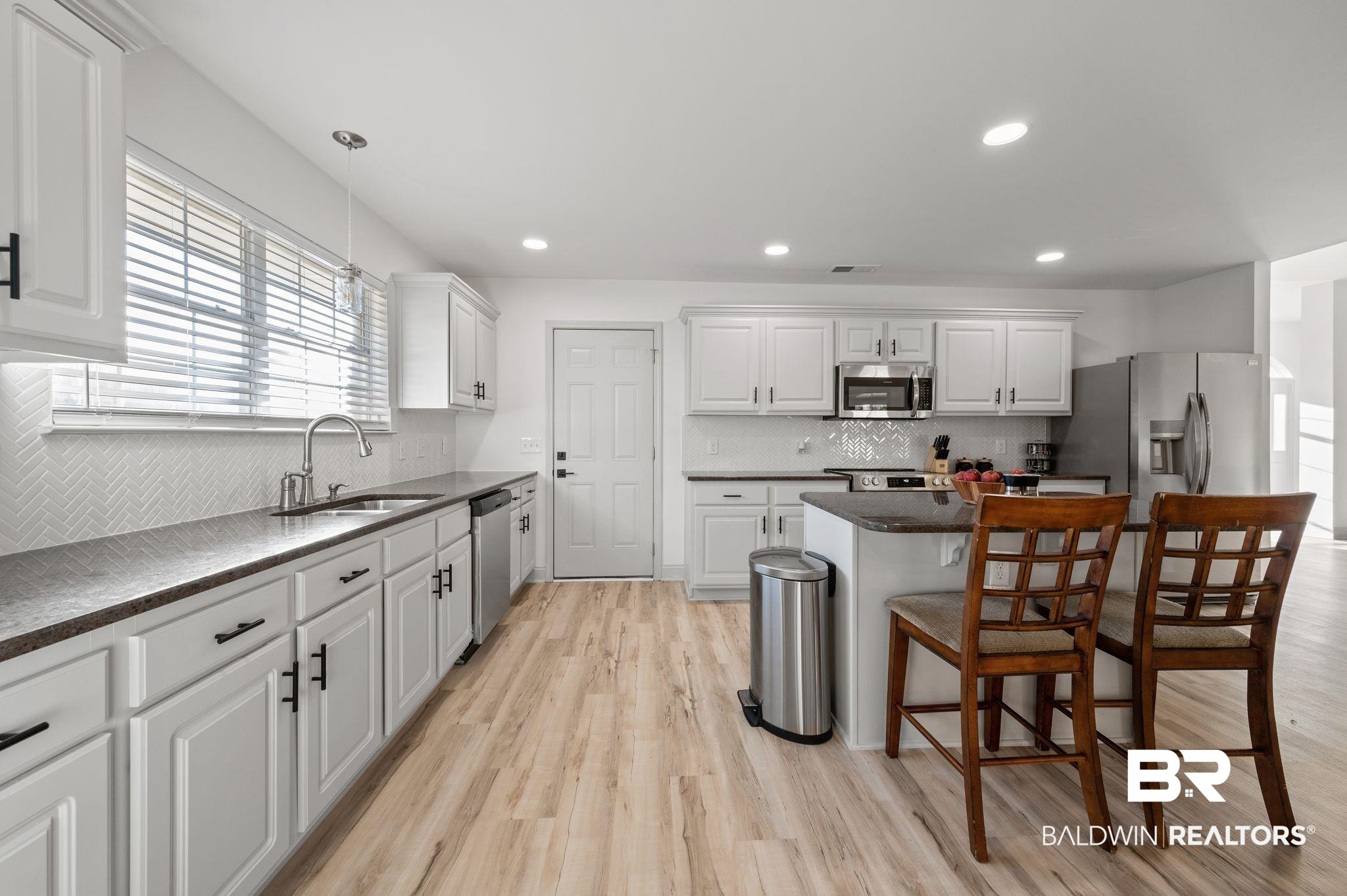 136 Destrehan Road Fairhope, AL 36532 - Photo 14 of 44 Kitchen featuring white cabinetry, light wood-type flooring, appliances with stainless steel finishes, pendant lighting, and a kitchen breakfast bar