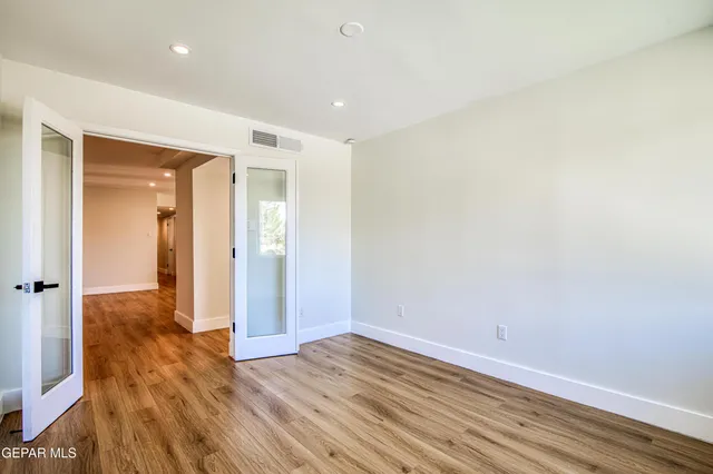 a kitchen with stainless steel appliances granite countertop a stove a sink dishwasher a refrigerator and white cabinets with wooden floor