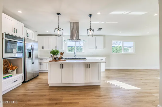 a kitchen with stainless steel appliances kitchen island granite countertop a sink stove and refrigerator