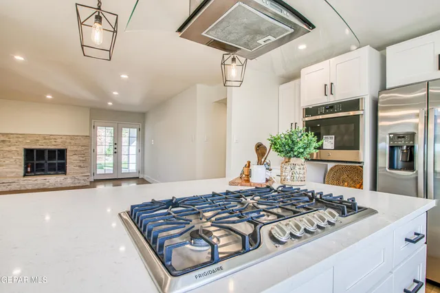 a kitchen with stainless steel appliances granite countertop a sink dishwasher a stove a dining table and chairs with wooden floor