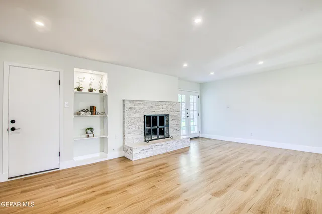 an empty room with wooden floor fireplace and windows