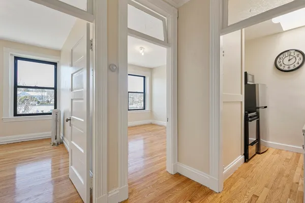 a view of a hallway with wooden floor and a bathroom