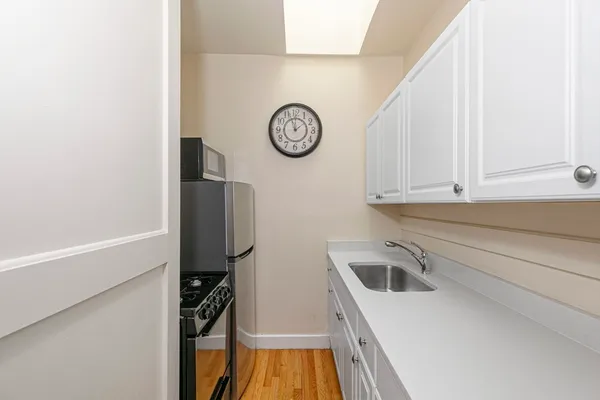 a view of a kitchen with fridge and wooden floor