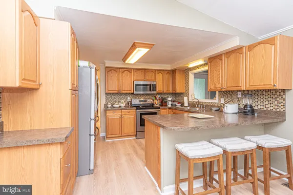 a kitchen with stainless steel appliances granite countertop a stove a sink dishwasher and a refrigerator with wooden floor