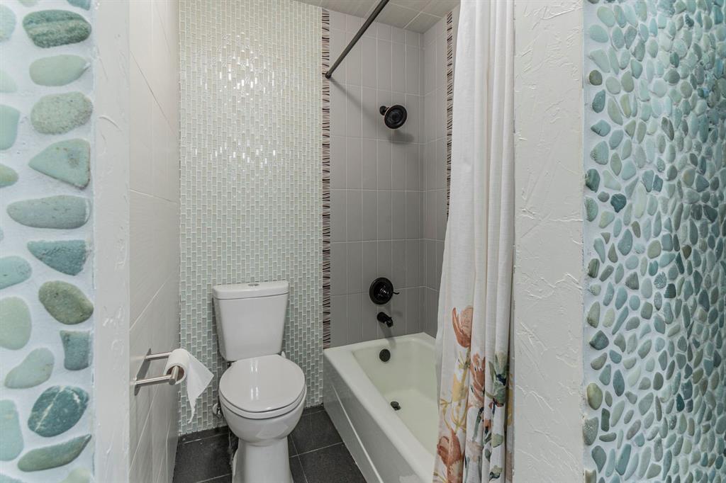 127 Nicklaus Nook Lancaster, TX 75146 - Photo 20 of 37 Full bath featuring shower / bathtub combination with curtain, dark tile patterned floors, and tile walls
