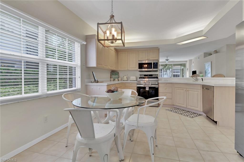 6923 Satinleaf Road North, Unit 101 Naples, FL 34109 - Photo 11 of 50 a kitchen with kitchen island a stove a table and chairs in it