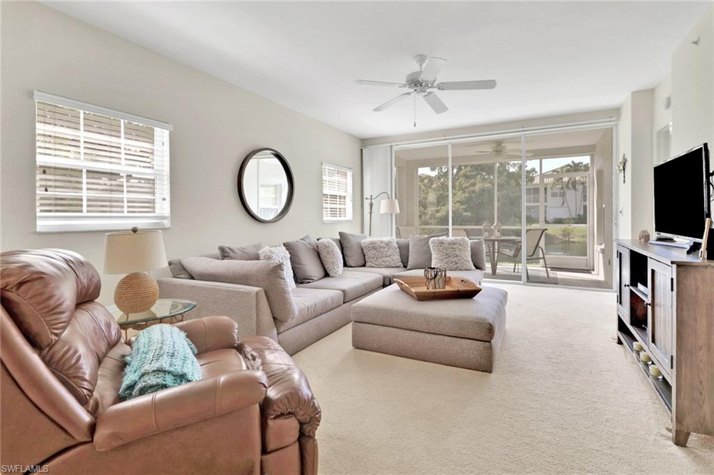 6923 Satinleaf Road North, Unit 101 Naples, FL 34109 - Photo 3 of 50 a living room with furniture a flat screen tv and a large window