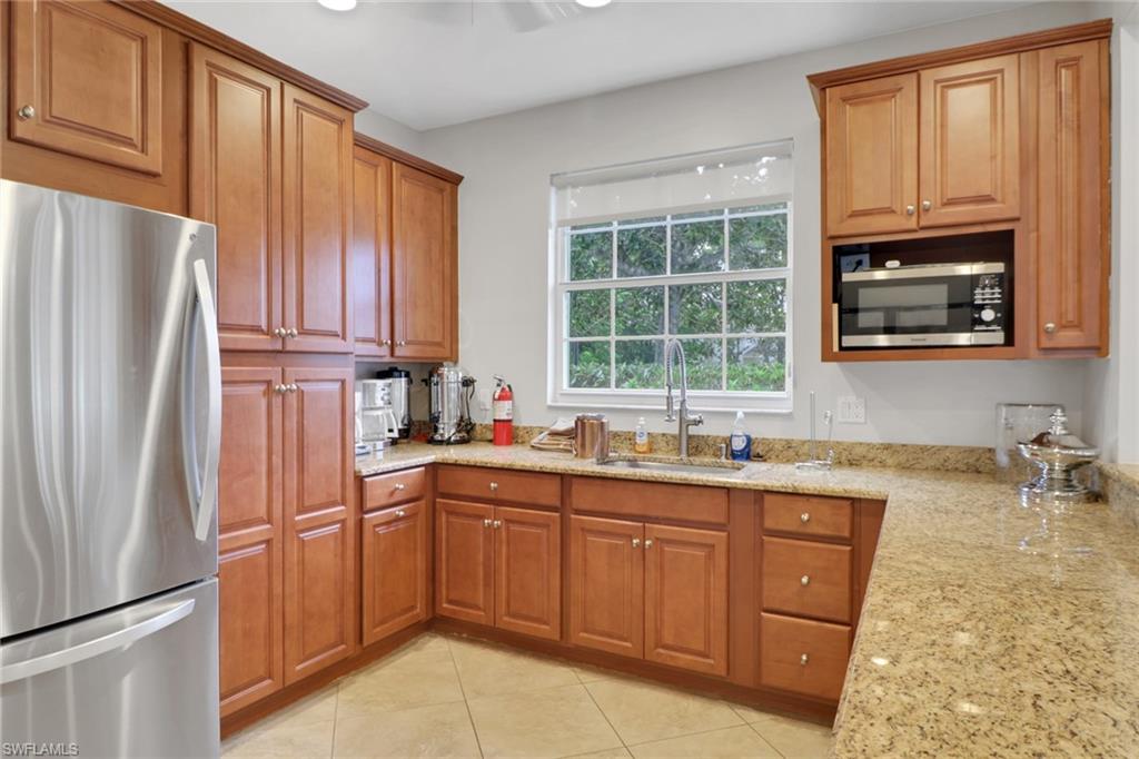 6923 Satinleaf Road North, Unit 101 Naples, FL 34109 - Photo 43 of 50 a kitchen with stainless steel appliances granite countertop a refrigerator sink and stove