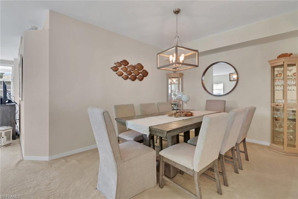 6923 Satinleaf Road North, Unit 101 Naples, FL 34109 - Photo 7 of 50 a view of a dining room with furniture a chandelier and wooden floor