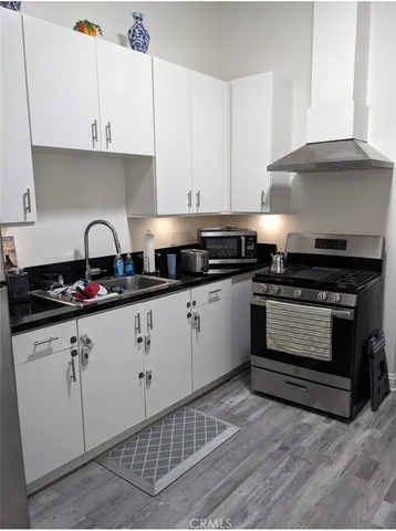 a kitchen with granite countertop a stove a sink dishwasher and white cabinets