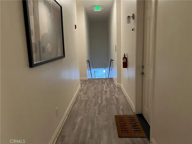 a view of a hallway with wooden floor and a bathroom