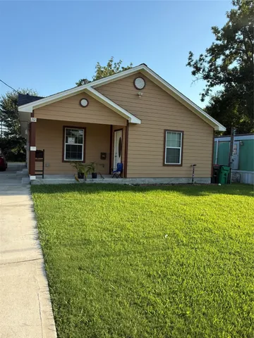 a front view of house with yard and trees in the background