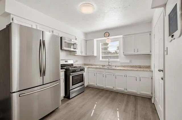 a kitchen with granite countertop stainless steel appliances a refrigerator stove top oven and sink