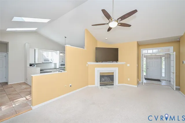 a view of a livingroom with a fireplace a ceiling fan and a kitchen