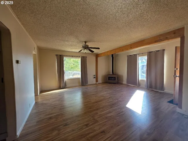 a view of a big room with wooden floor and windows