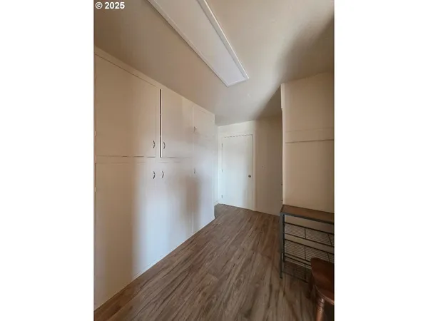 a view of a hallway with wooden floor and a cabinet