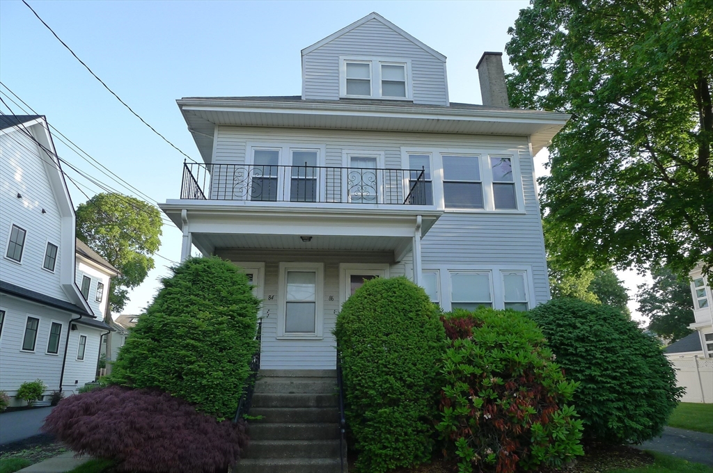 a front view of a house with plants and entryway