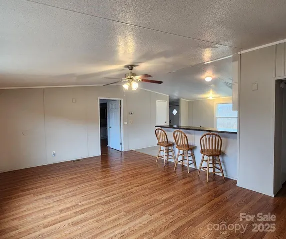 a view of a room with wooden floor kitchen view and a chandelier