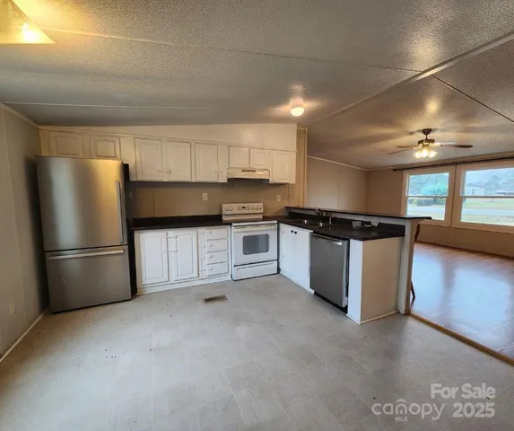 a kitchen with stainless steel appliances granite countertop a refrigerator a sink and a stove