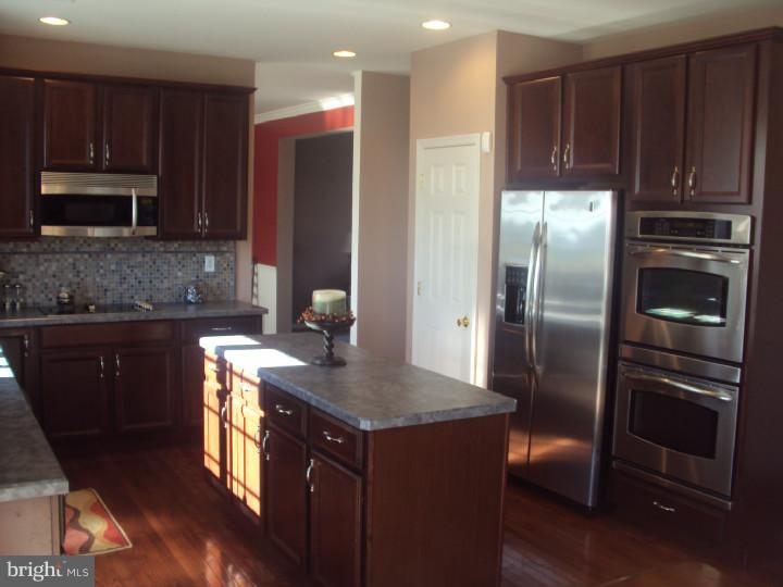 706 Farmhouse Road Mickleton, NJ 08056 - Photo 6 of 24 a kitchen with kitchen island granite countertop stainless steel appliances and wooden cabinets