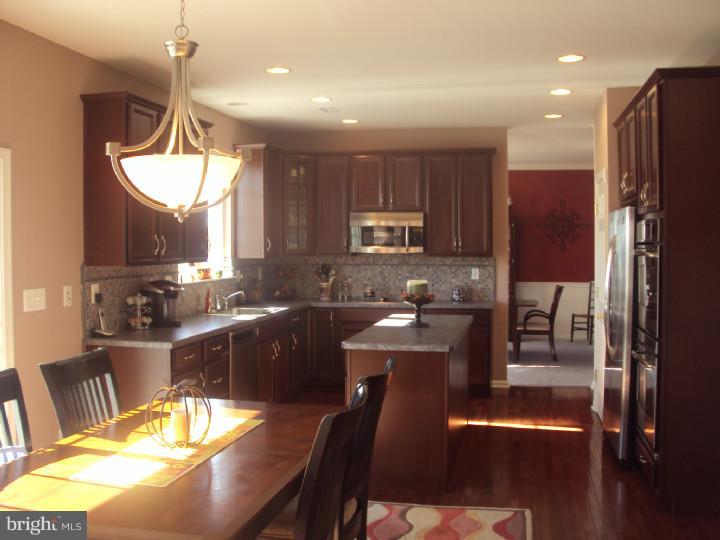 706 Farmhouse Road Mickleton, NJ 08056 - Photo 7 of 24 a kitchen with stainless steel appliances granite countertop a refrigerator a stove a sink a dining table and chairs with wooden floor