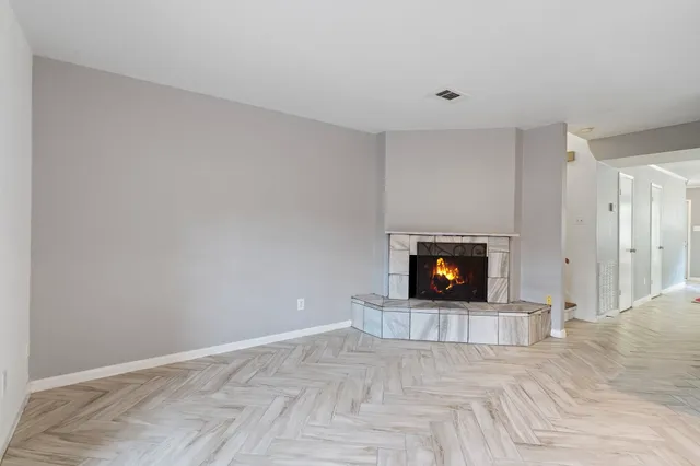 a view of an empty room with wooden floor and a fireplace