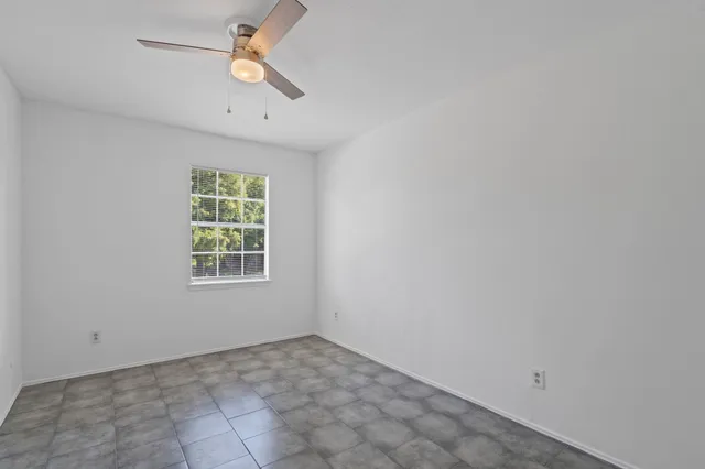 an empty room with a window and a ceiling fan